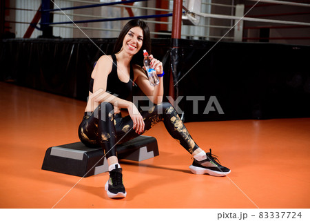 Attractive sports girl smiles and drinking water standing in fitness class. 83337724