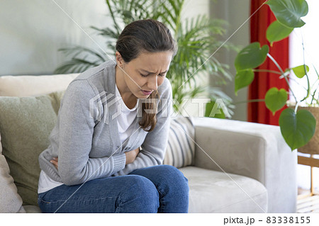 Young woman suffering PMS pain on sofa. 83338155