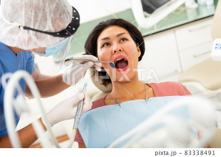 Female patient sitting in dental chair. Dentist is treating female patient closeup Female patient sitting in dental chair. Dentist is treating female patient closeup 83338491