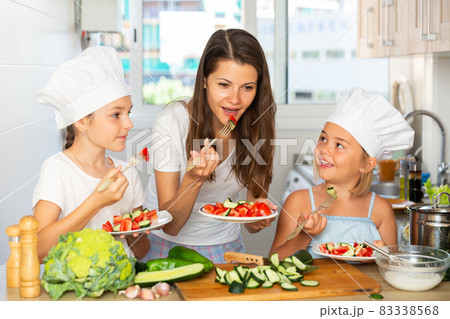 Happy family mom and her little daughters are preparing food Happy family mom and her little daughters are preparing food 83338568