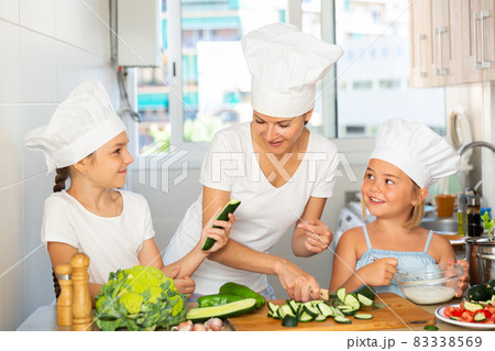 Happy family mom and her little daughters are preparing food Happy family mom and her little daughters are preparing food 83338569