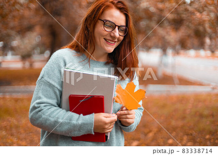 Beautiful female college student with books in a park 83338714