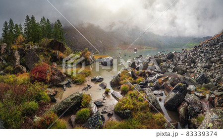 Panoramic view of the autumn mountain, fog over the mountain slopes in the distance, white clouds filling the mountain gorge. A clear blue mountain lake and a bright autumn forest. Panoramic view of the autumn mountain, fog over the mountain slopes in the distance, white clouds filling the mountain gorge. A clear blue mountain lake and a bright autumn forest. 83339374