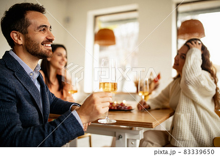 Cropped portrait of smiling man drinking white wine, having cheerful meeting with friends at cafe on warm sunny day 83339650
