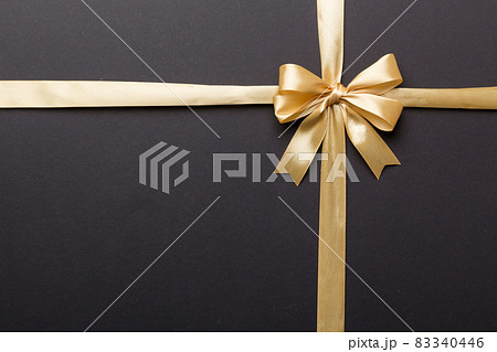 Top view of gold ribbon rolled and yellowbow isolated on colored background. Flat lay with copy space 83340446