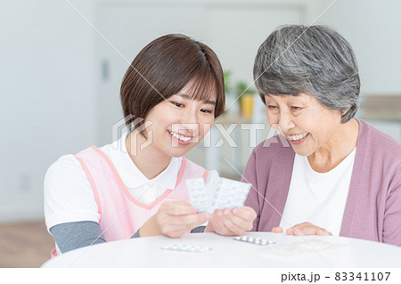 訪問診療　介護士さんに薬の説明をしてもらう高齢の女性 83341107