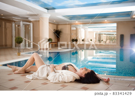 Spa Relaxation. Beautiful caucasian girl in bikini near the pool in resort day spa salon. 83341429