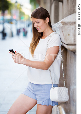 Young woman standing with phone near building Young woman standing with phone near building 83341825