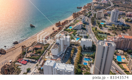 Aerial view of the city of Portimao over residential buildings, high-rise buildings, on the beach Praia de Rocha with tourists. Sunny day 83343574