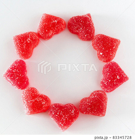 The circular arrangement of sweet red fruit jelly in the shape of a heart. Symbol of the day of lovers. Place for your text. The circular arrangement of sweet red fruit jelly in the shape of a heart. Symbol of the day of lovers. Place for your text. 83345728