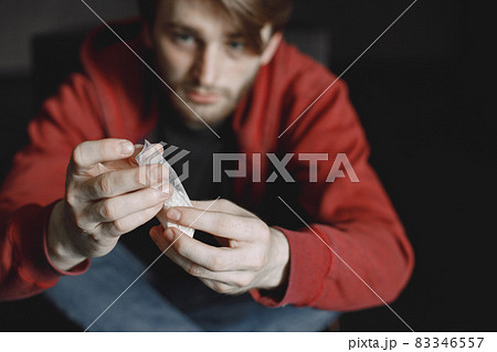 Young addicted man with cocain packet sitting alone Young addicted man with cocain packet sitting alone 83346557