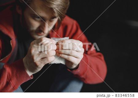 Young addicted man with cocain packet sitting alone Young addicted man with cocain packet sitting alone 83346558
