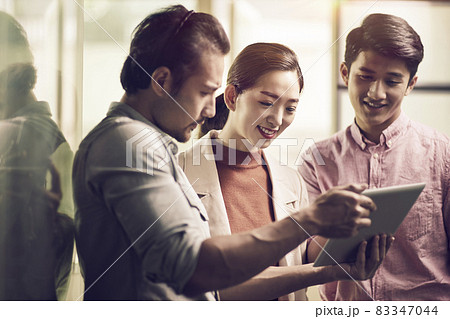 three young asian businessmen entrepreneurs working together in office looking at digital tablet 83347044