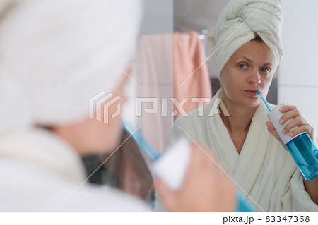Woman in the bathroom conducts hygienic cleaning of teeth 83347368