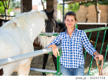 Positive female farmer who is standing near corral at the farm Positive female farmer who is standing near corral at the farm 83347758