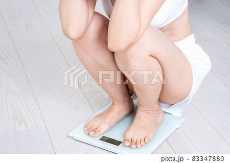 トレーニングウェアで体重を計る女性【パーツカット】 83347880