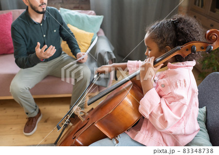 Cute little biracial girl gliding fiddlestick across cello strings Cute little biracial girl gliding fiddlestick across cello strings 83348738