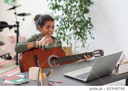 Happy preteen schoolgirl waving hand to her teacher during online lesson Happy preteen schoolgirl waving hand to her teacher during online lesson 83348788
