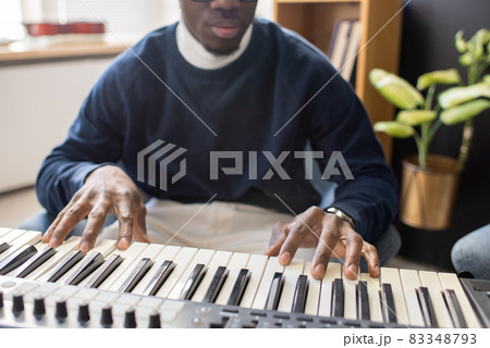 Hands of young music teacher of African ethnicity playing piano keyboard 83348793