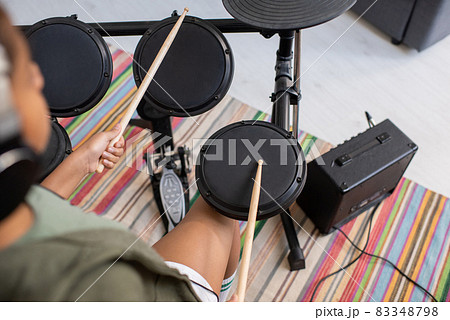 Schoolgirl with wooden drumsticks hitting one of drums Schoolgirl with wooden drumsticks hitting one of drums 83348798