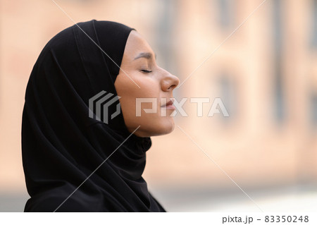 Outdoor Profile Portrait Of Calm Young Muslim Woman In Black Hijab 83350248