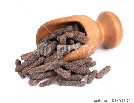 Long pepper in wooden scoop, isolated on white background. Heap of pippali or piper longum. Long pepper in wooden scoop, isolated on white background. Heap of pippali or piper longum. 83351134