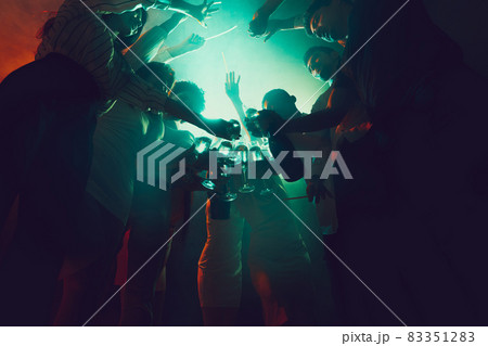 Group of young, active people at the night club, party dancing in neon lights, drinking cocktails 83351283