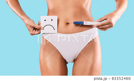 Sad woman holding positive pregnancy test wearing white underwear Sad woman holding positive pregnancy test wearing white underwear 83352460