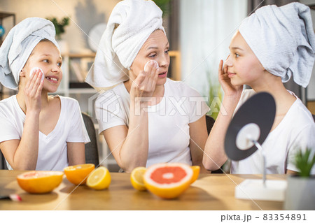 Happy mother teaching her daughters to take care of skin 83354891