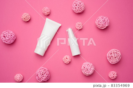 bottle and empty white plastic tubes for cosmetics on a pink background. Packaging for cream, gel, serum, advertising and product promotion, mock up 83354969