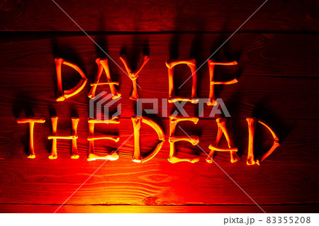 Lettering from the bones of the words Day of the Dead on a beautiful dark red wooden background. Design to celebrate Dia de los Muertos. Scary inscription. Copy space for text. Close-up 83355208