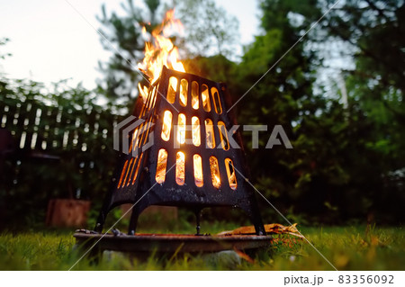 A burning a bonfire in a fire bowl on a summer evening in the backyard. Burning firewood in a fire bowl. 83356092