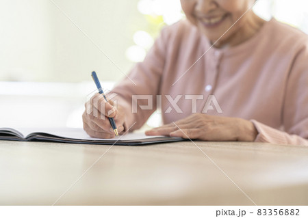 ペンを持ったシニア女性の手元 83356882