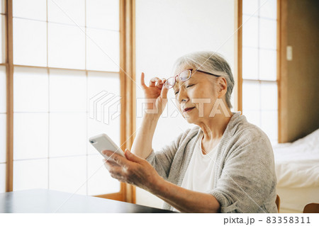 スマホを使う高齢者女性（老眼） 83358311