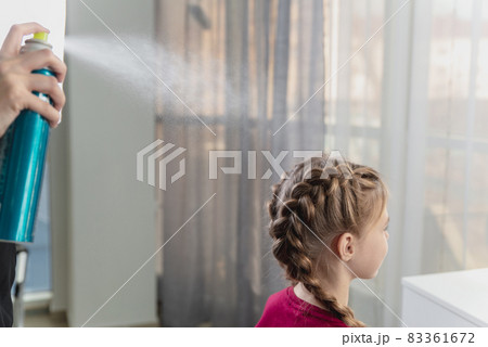 Hairdresser weaves a braid to a preteen blond girl in a beauty and hair salon 83361672