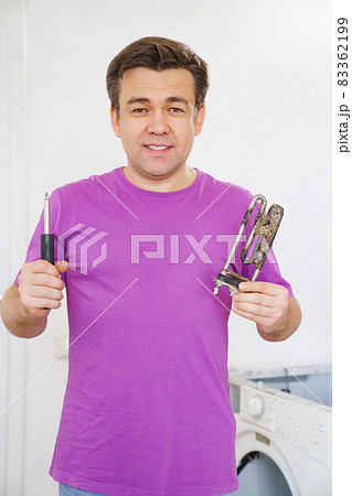 repairman of washing machine holds old tubular electric heater and screwdriver repairman of washing machine holds old tubular electric heater and screwdriver 83362199