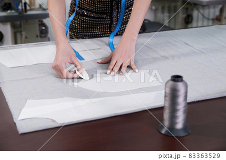 Tailor at work, drawing line on fabric with chalk in atelier studio Tailor at work, drawing line on fabric with chalk in atelier studio 83363529