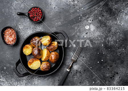 Baked potatoes , in frying cast iron pan, on black dark stone table background, top view flat lay, with copy space for text Baked potatoes , in frying cast iron pan, on black dark stone table background, top view flat lay, with copy space for text 83364215