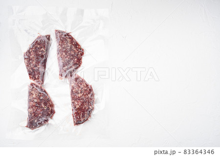 Beef veal cutlets in vacuum plastic pack, on white stone table background, top view flat lay, with copy space for text Beef veal cutlets in vacuum plastic pack, on white stone table background, top view flat lay, with copy space for text 83364346
