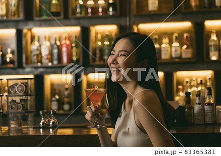 Asian women drinking cocktails and having fun at the bar at night. 83365381