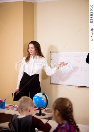 Primary school kids sitting at school class and listening to a teacher at lesson. 83365910