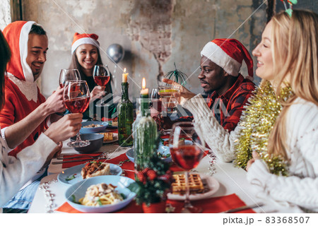 People celebrating sitting at the table, clinking glasses. Christmas or New Year eve. 83368507