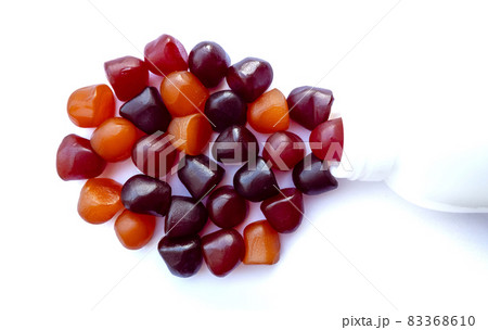 Group of red, orange and purple multivitamin gummies with the bottle isolated on white background. Group of red, orange and purple multivitamin gummies with the bottle isolated on white background. 83368610