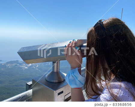 The girl looks at the mountains and the sky from a large fortress wall in the city of Antalya in Turkey. It uses a monocular, a telescope, binoculars and this service is paid 83368656