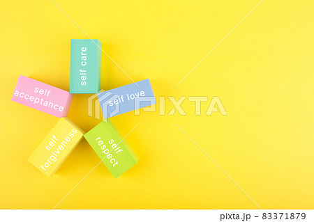 Mental health formula concept. Self acceptance, self care, self respect and self forgiveness written on flower from multicolored rectangles on yellow background with copy space Mental health formula concept. Self acceptance, self care, self respect and self forgiveness written on flower from multicolored rectangles on yellow background with copy space 83371879