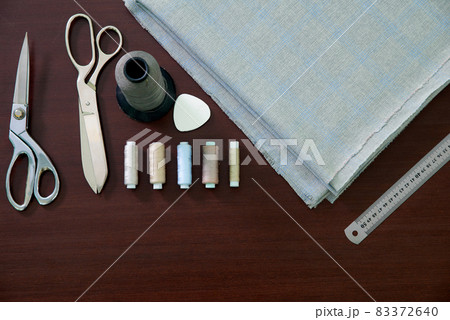 Group of sewing objects lying on a wooden table, flat lay concept of tailor shop Group of sewing objects lying on a wooden table, flat lay concept of tailor shop 83372640