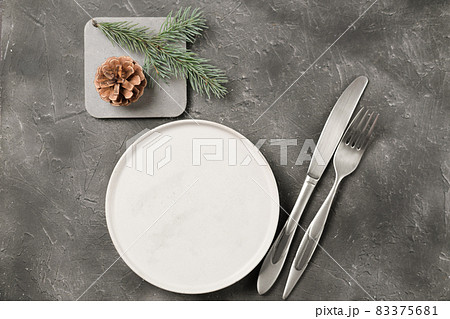 empty plate with silverware and christmas tree branch and cone on grey table. copy space. table setting template for new year or christmas menu. restaurant menu mock up. top view 83375681