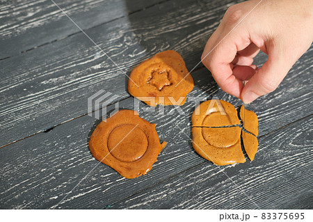 hand breaking dalgona candy Squid game ppopgi, Korean sweets with stamps in the center. Viral trend on cocial media. 83375695