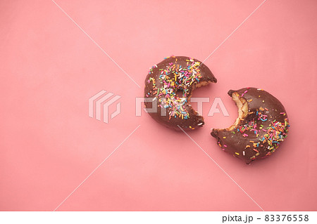 top view of half eaten chocolate donuts on pink  83376558