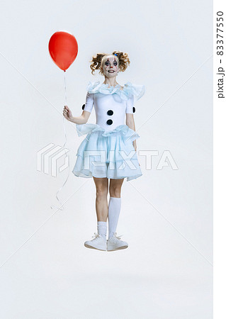 Full-length portrait of young girl wearing Halloween dress, costume of clown jumping isolated over grey background 83377550